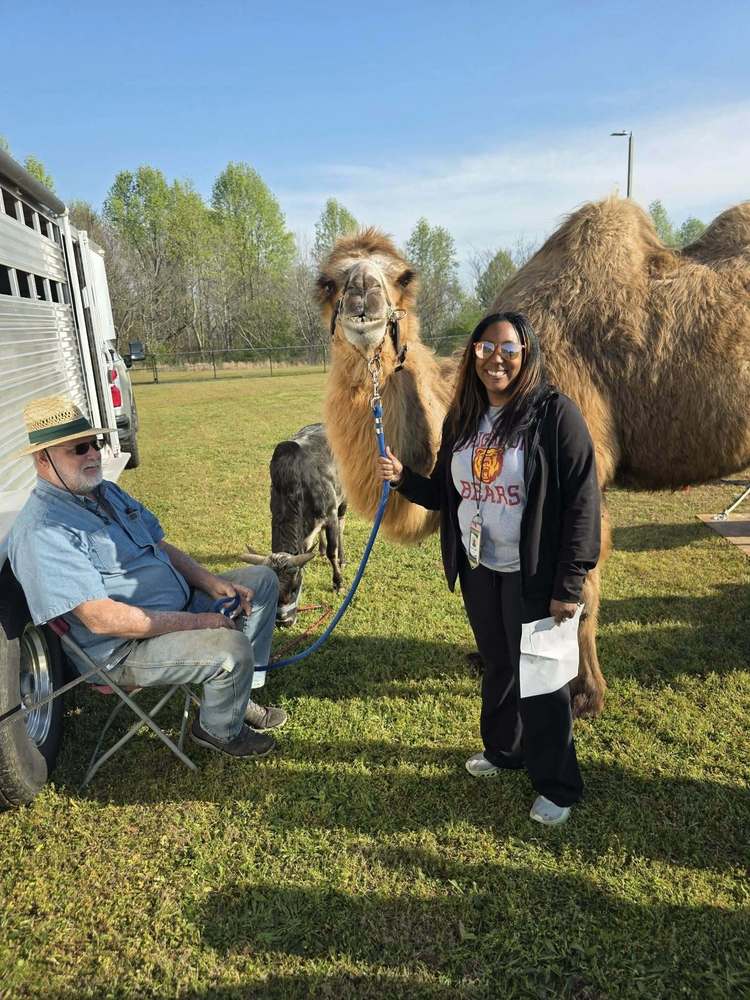 teacher and zookeeper posing with a two humped camel