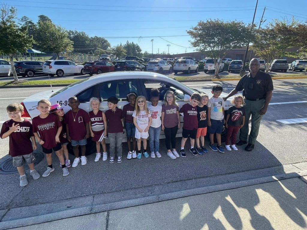 group of kindergartners posing in front of a police car