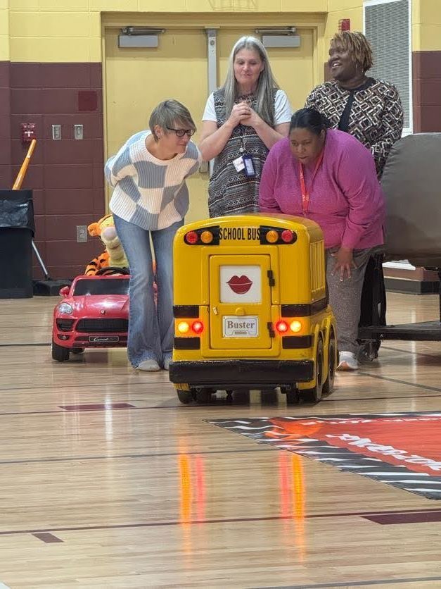 teachers beending over and looking at the toy school bus