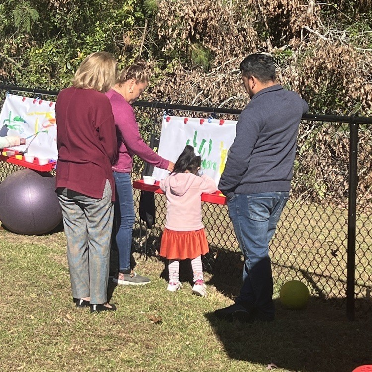 Adults watch as a young students paints. This is part of the new sensory garden at Grantswood Community School.