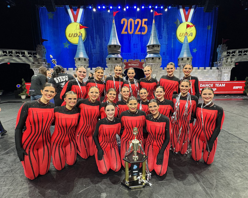Gardendale High School Dance Team poses in front of 2025 banner at National Championship. They are wearing bright red and black outfits and they have the 4th place trophy placed in front of them.