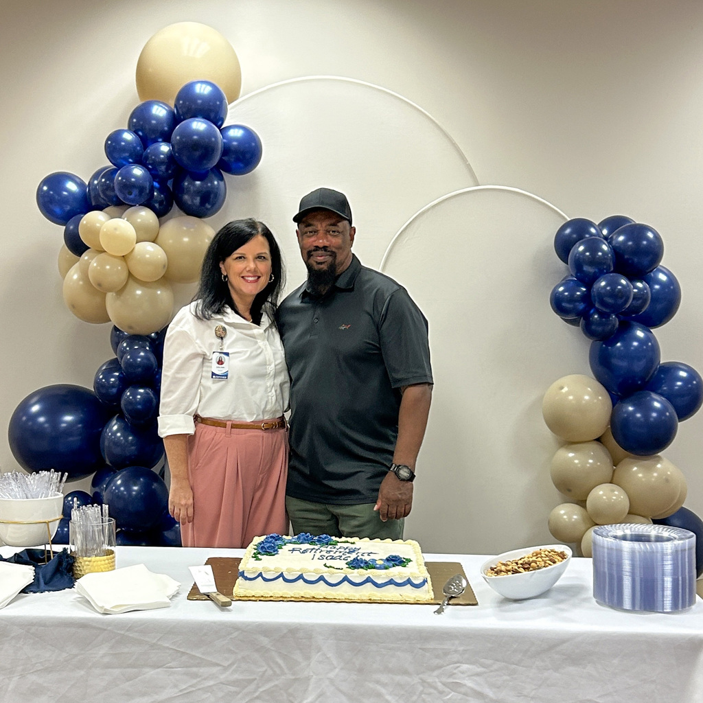 Sara Fenn and Issac Pettway stand in front of decorations at Issac's retirement party.