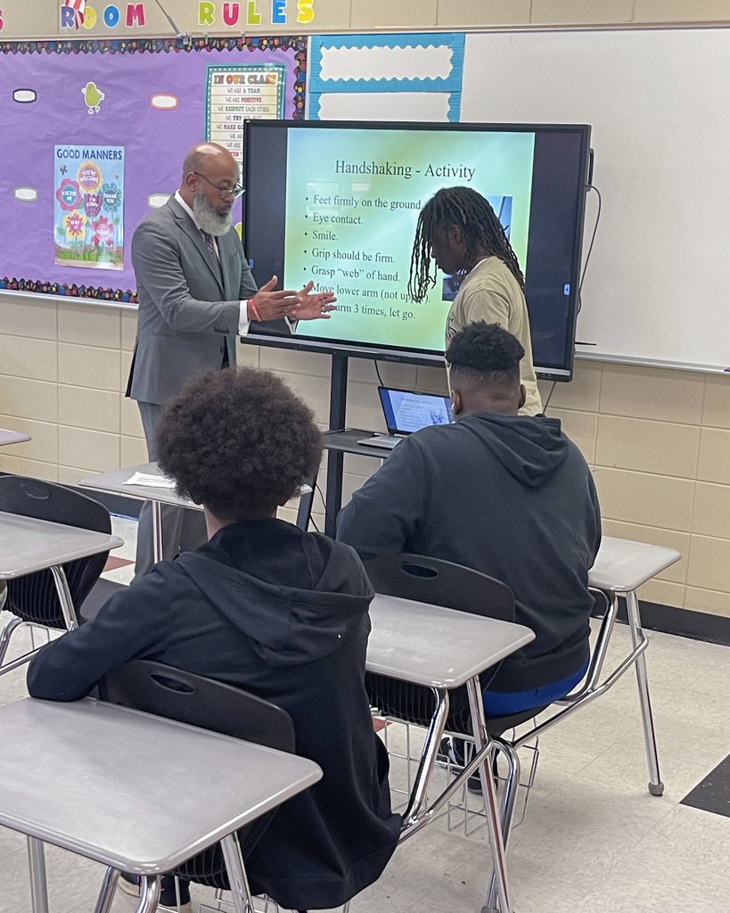 Student and presenter take part in a handshaking activity during the Male presenter speaks to students during the Brotherhood & Girl Code Empowerment Summit 2025 at McAdory Middle School.