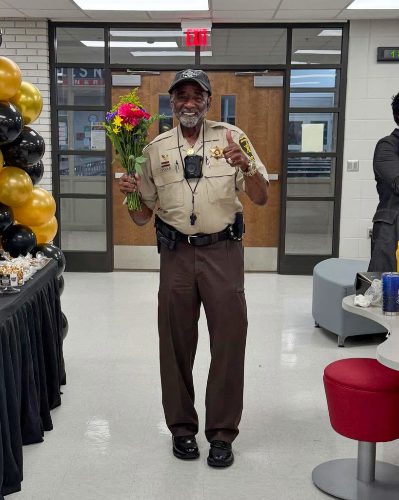 Deputy Eric Poole is holding up flowers and celebrating his retirement from Erwin Middle School and Law Enforcement after 42 years of service.