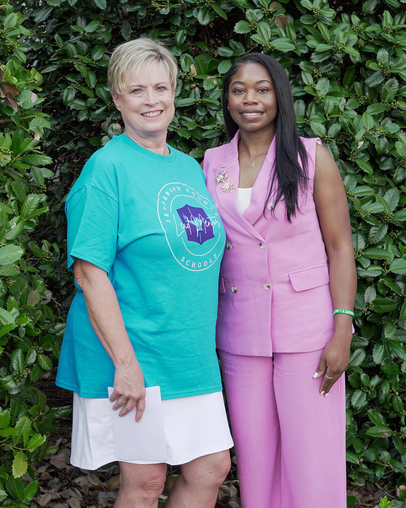 Leslie Chatta and Shernell Lewis posing for a picture with greenery behind them.