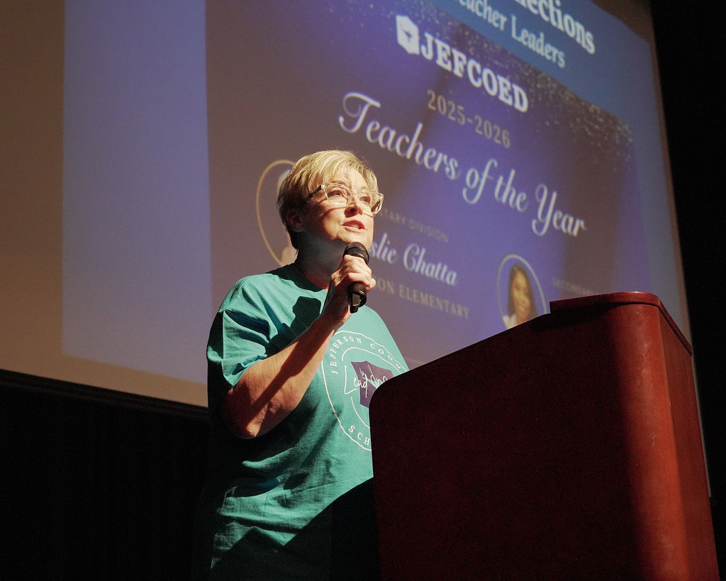 Leslie Chatta holding a microphone and presenting on stage.