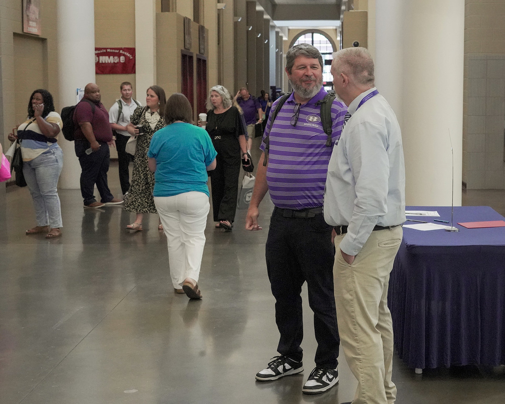 Teachers walking and visiting in a hallway.