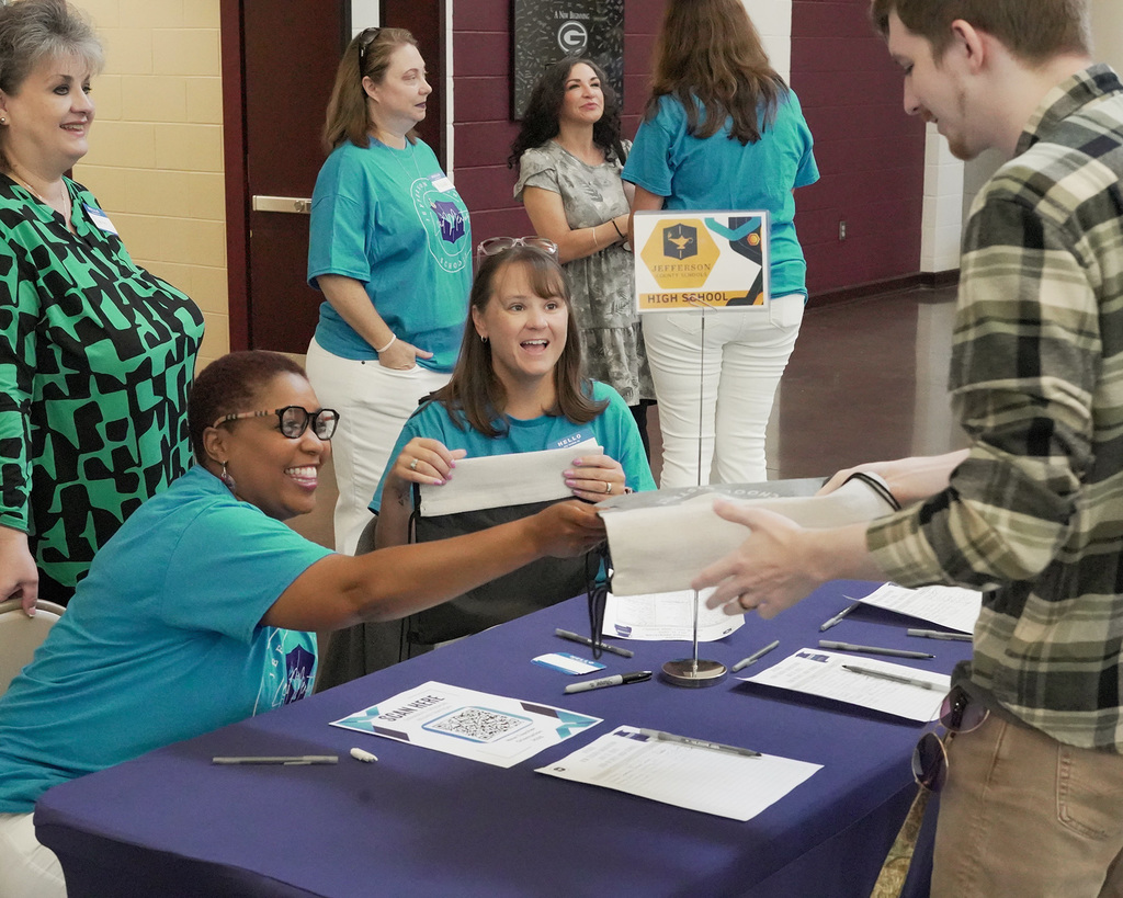 School employees greeting educators at a registration desk.