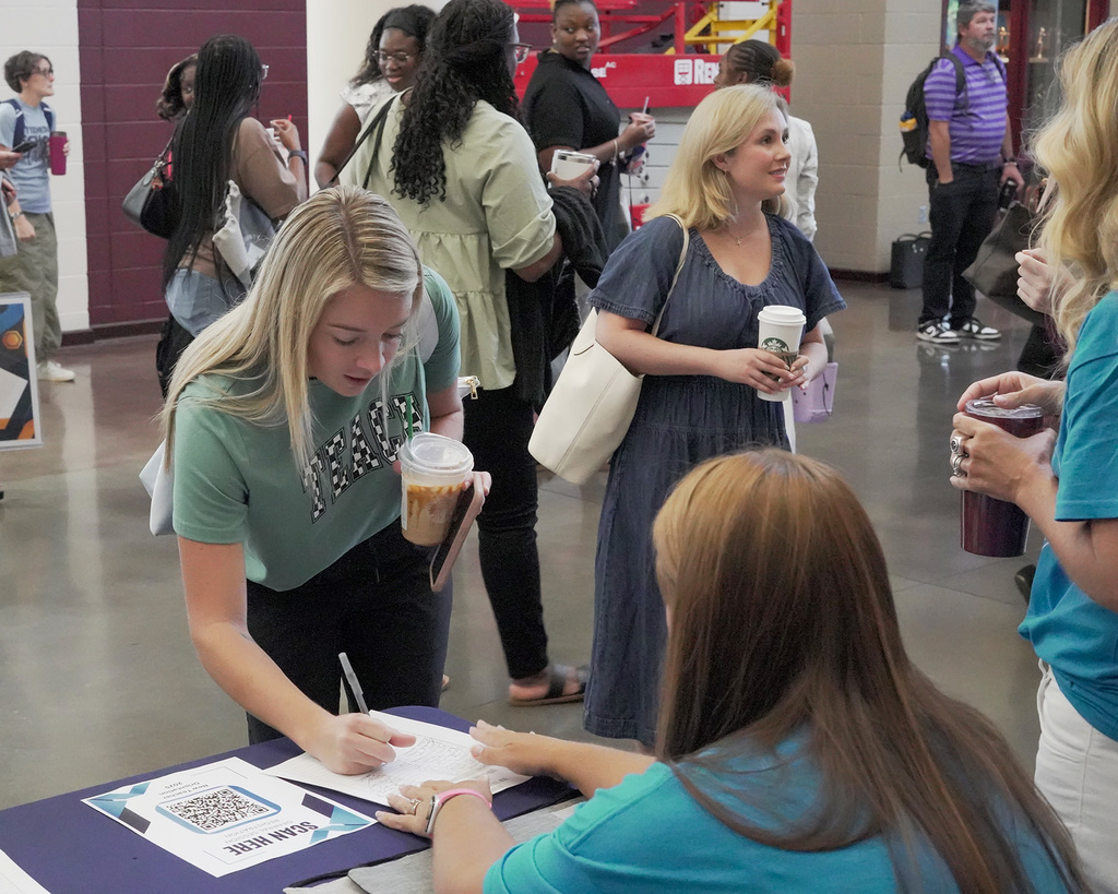 Teachers signing in at a registration table for New Teacher Orientation.