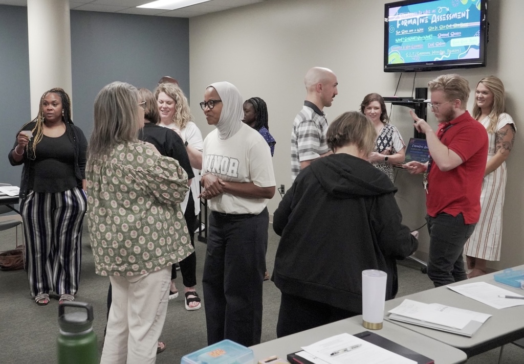 A group of people stand in a room and talk to each other.