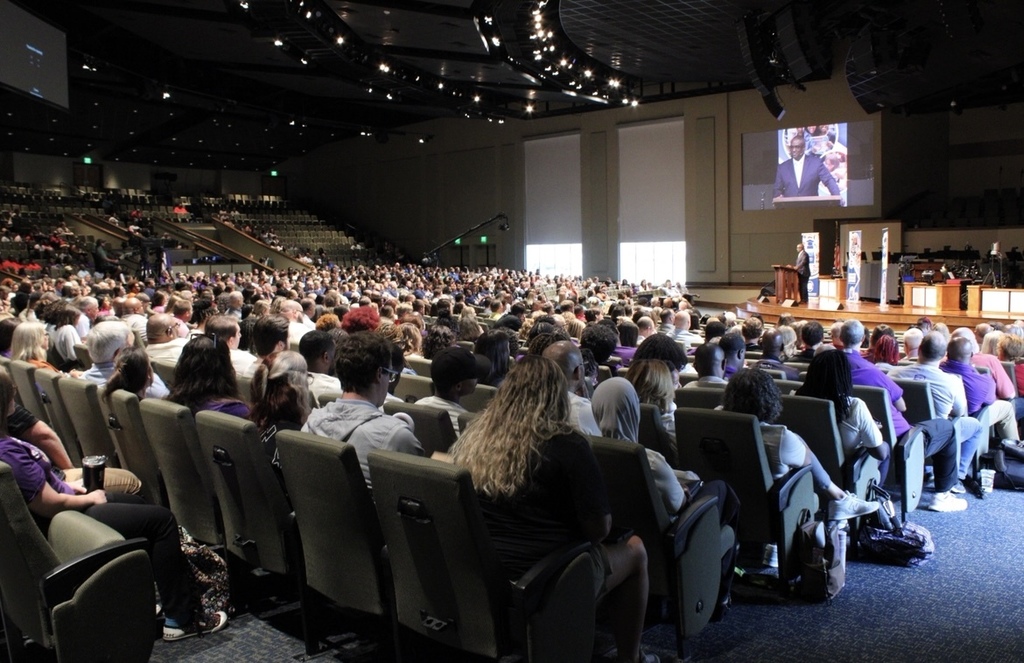 A large group of people sit in an auditorium