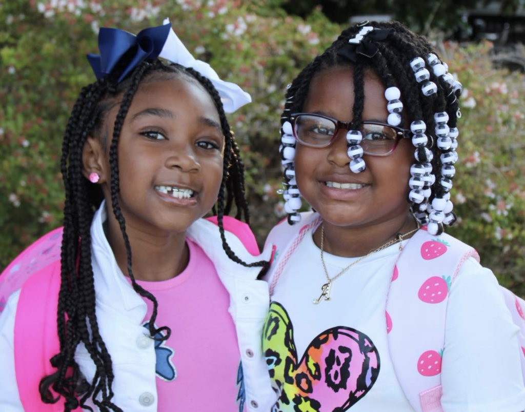 Two young girls stand together and smile