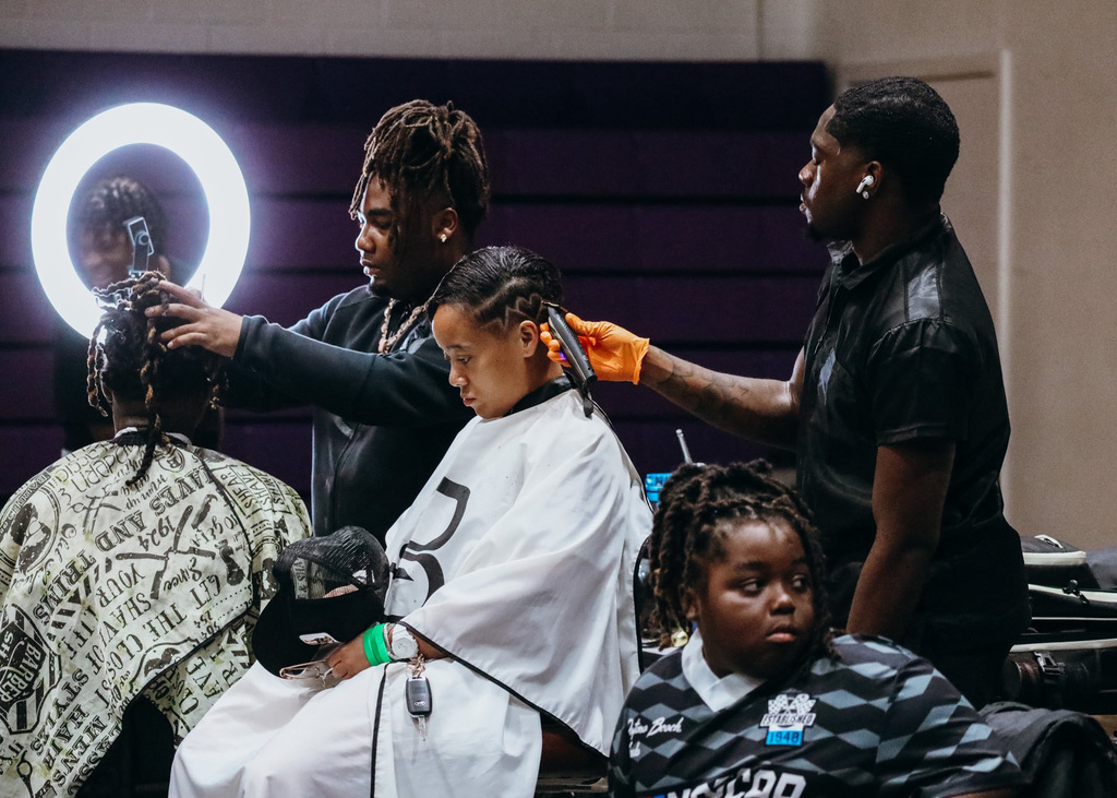 Three children sit in salon chairs while they get their hair cut