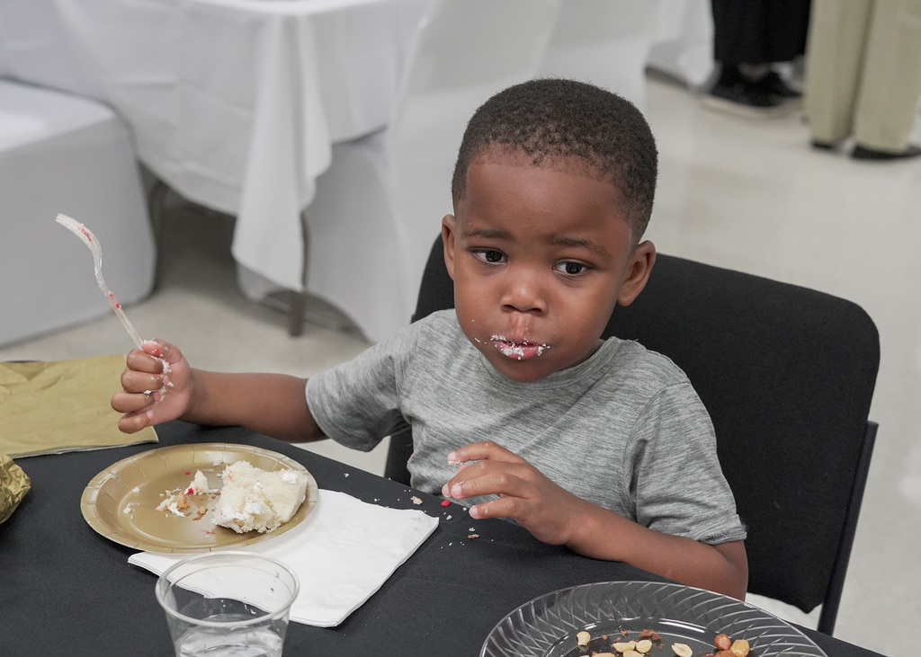 A little boy with frosting on his face eats cake.