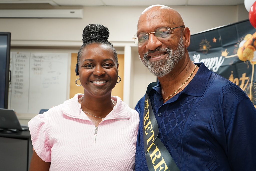 A man and a woman stand together and smile at the camera.
