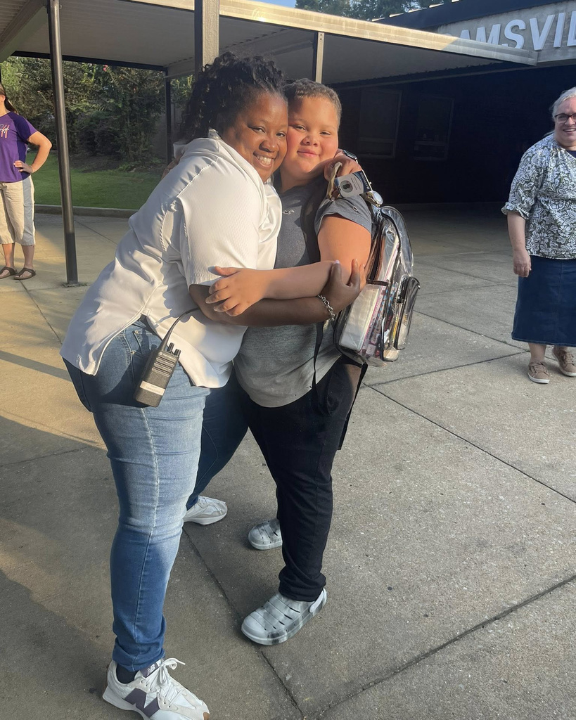 A student receives a big hug upon arrival to school.