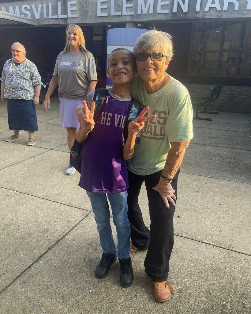 A student and a parent smile for the camera. The student his holding up peace signs.
