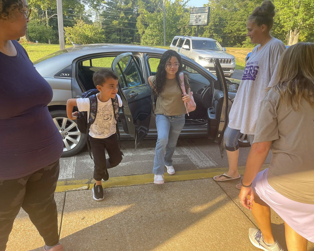 Two students exit a car during morning car line at school.