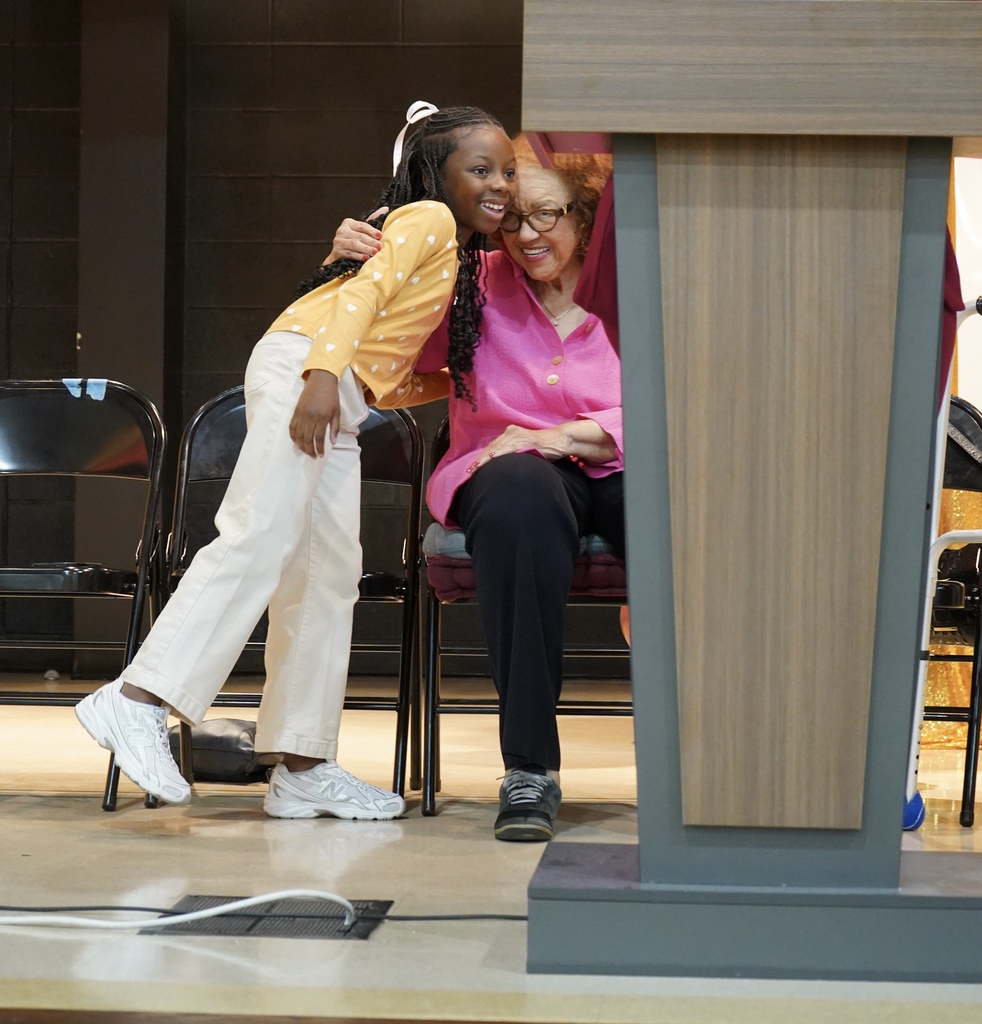 A little girl stands and hugs a woman who is sitting down