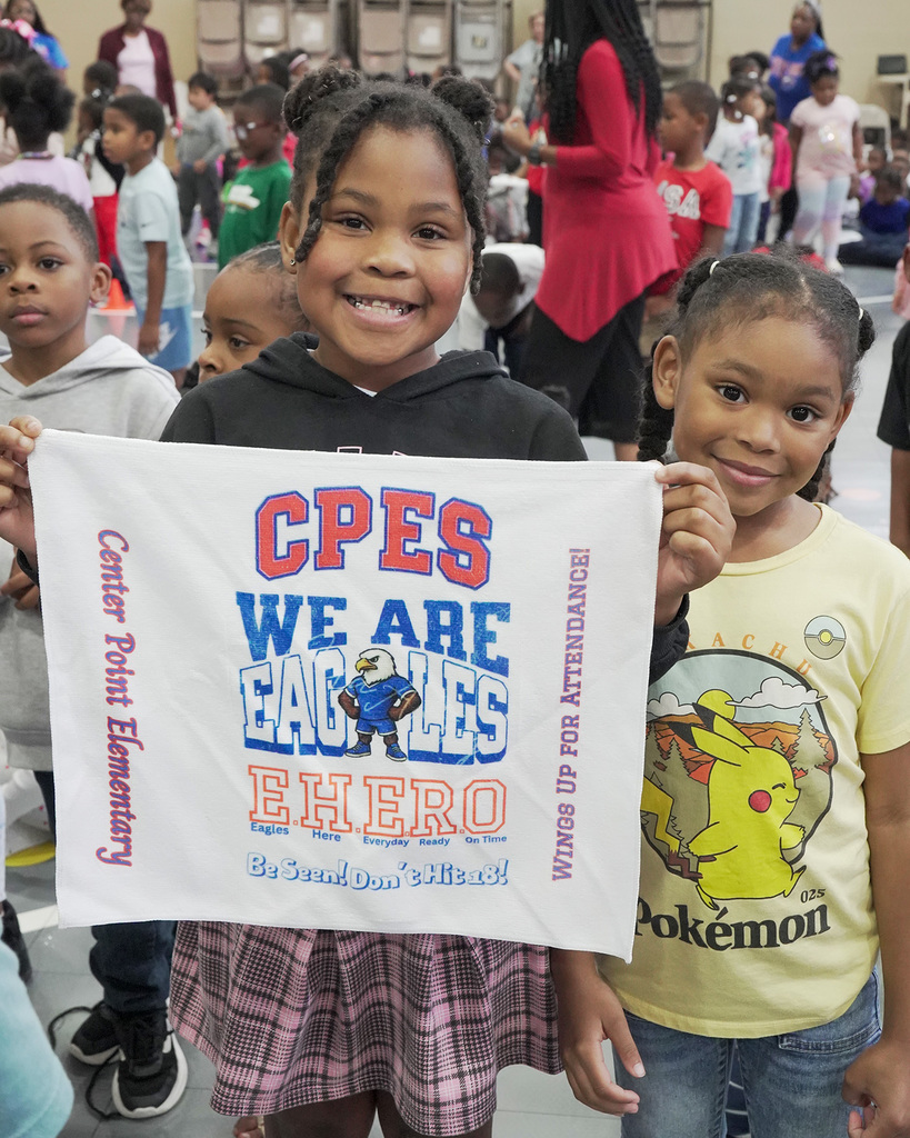 A student holds up a towel that says CPES We are Eagles. EHERO. Be Seen. Don't Hit 18. Wings Up for Attendance. Center Point Elementary.