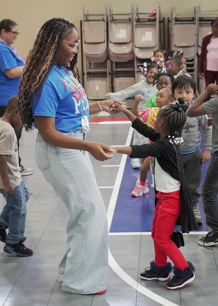 A teacher and student dance together during a school pep rally.
