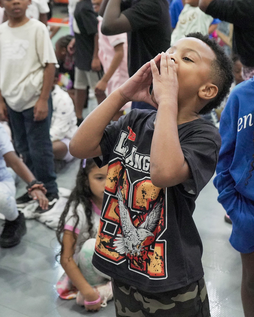 A student holds his hands up to his face as he yells during a pep rally.