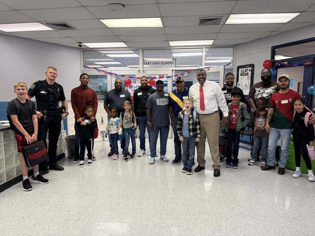 A group of men and students stand together and smile.