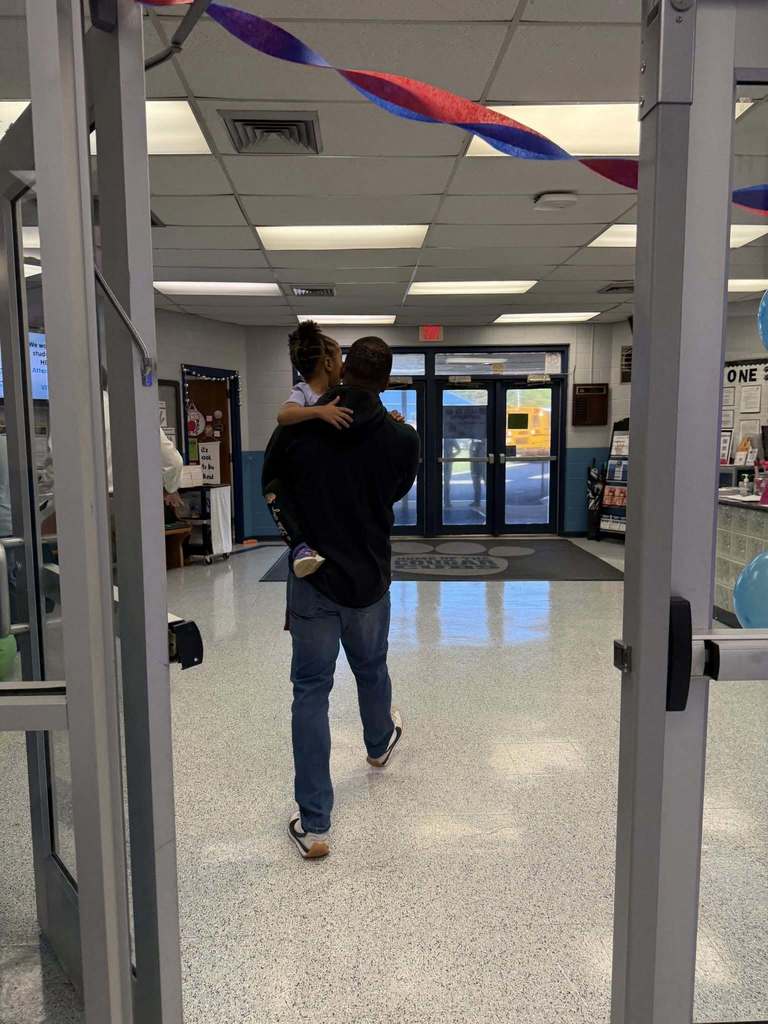 A man carries a child through an elementary school.