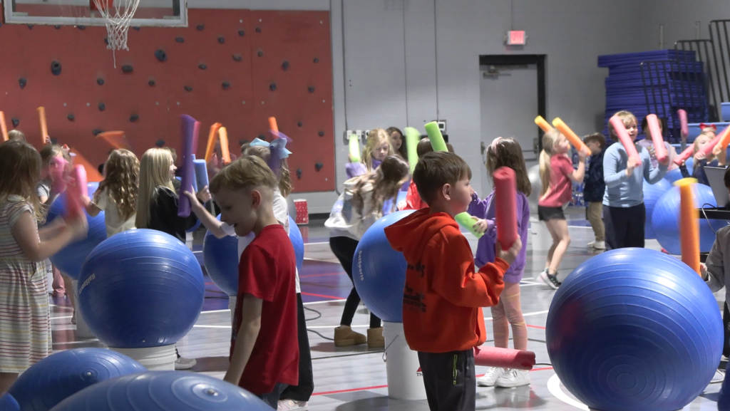 Children play with yoga balls inside a gym.