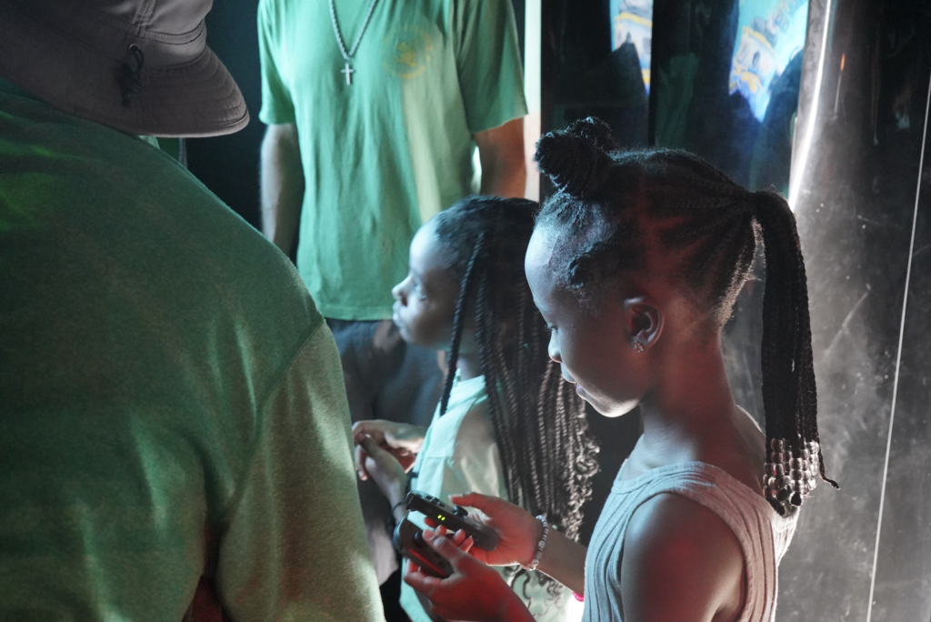 Little girls stand together and play video games.