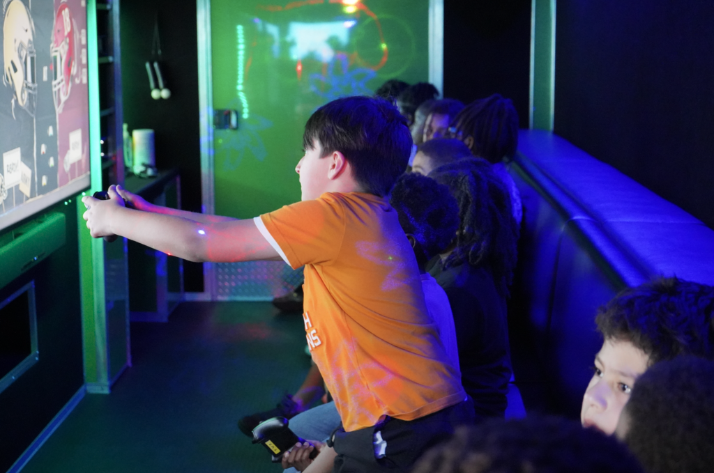 Young boys sit on a couch and play video games.