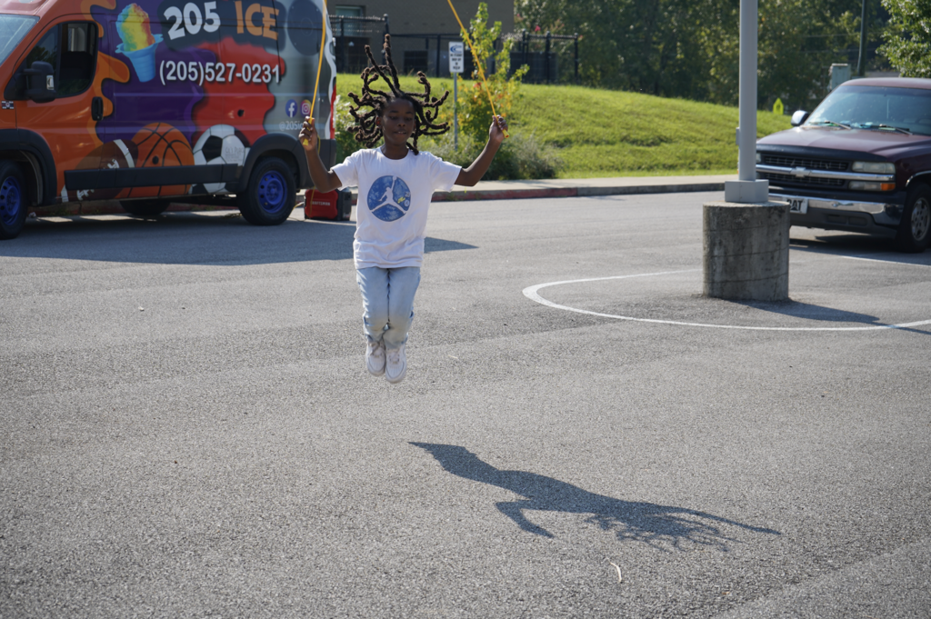 A boy jumps rope in a school parking lot.