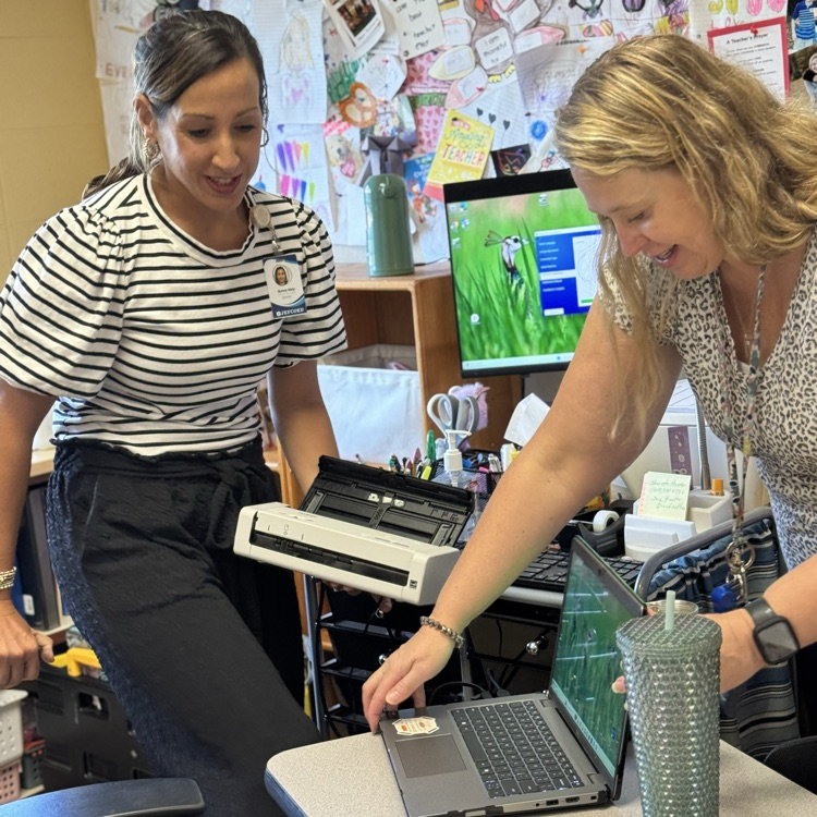 two teachers holding a laptop