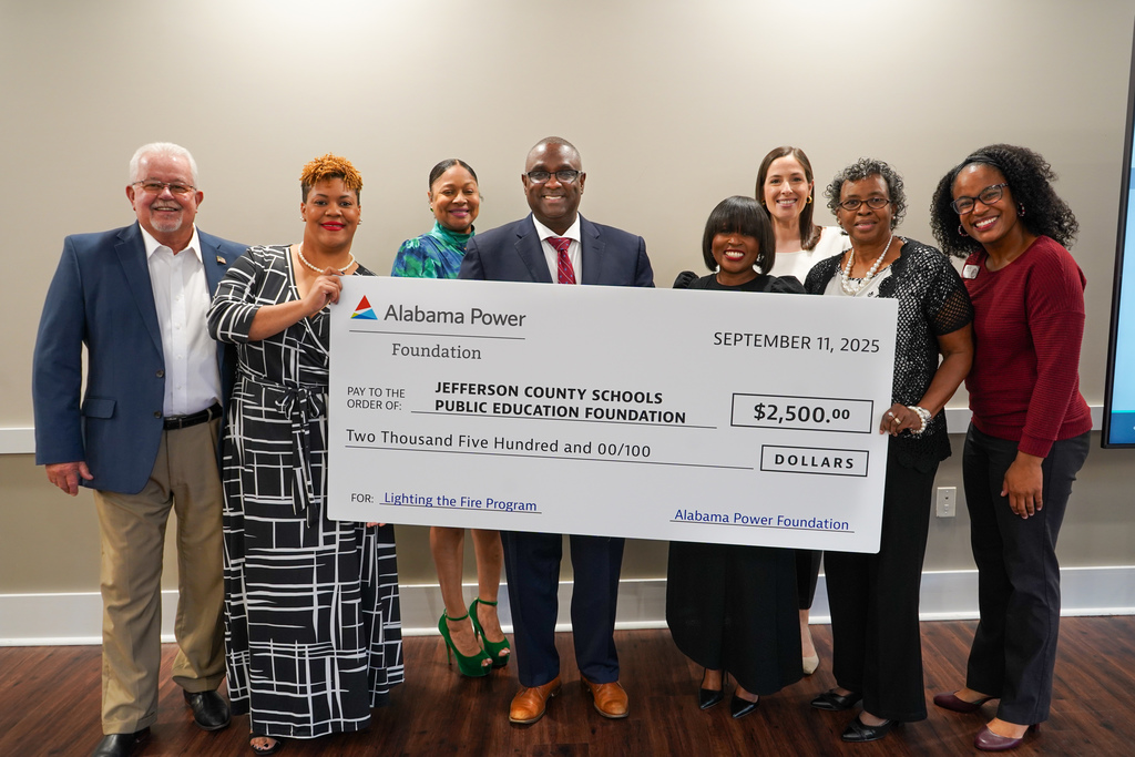 A group of people stand together, holding a big check from Alabama Power, to the Jefferson County Schools Education Foundation.