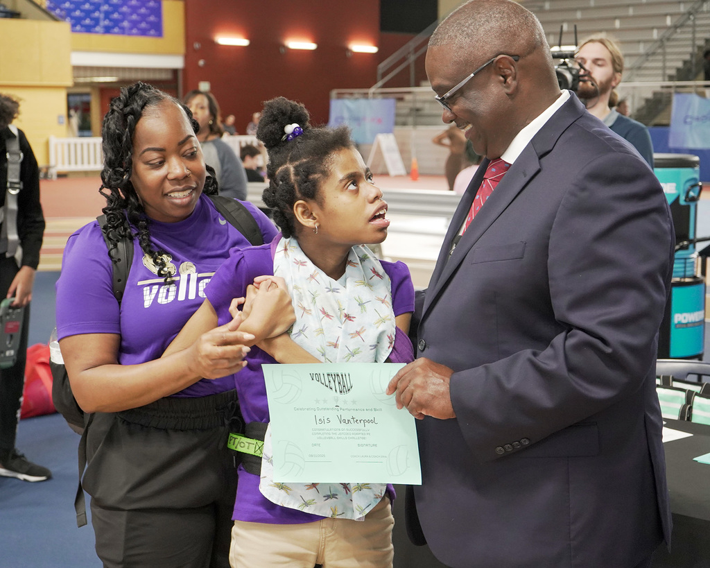 A female student receives a certificate from the superintendent following her participation in an adaptive volleyball tournament. 