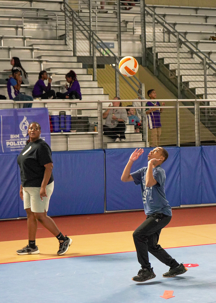 A male student participates in an adaptive PE volleyball event. He is looking up at the ball as it comes down. 