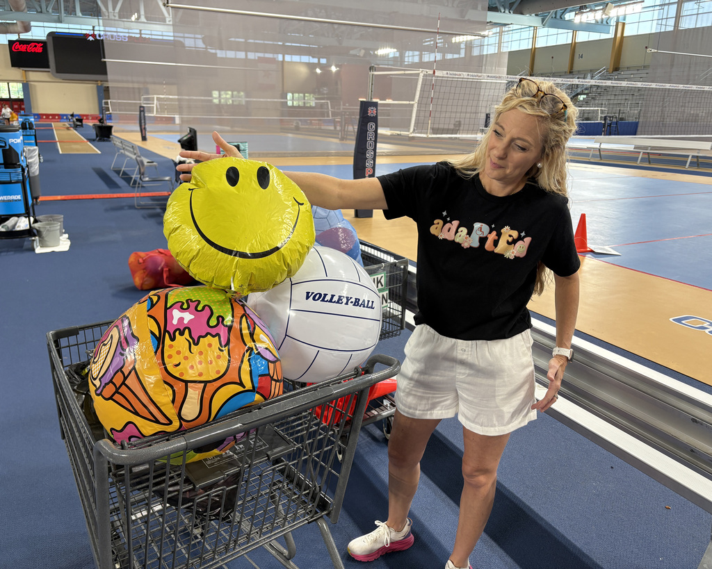 An adapted PE instructor shows colorful large volleyballs used during an adaptive PE event. 