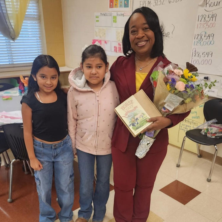 two students and a teacher smiling and holding flowers