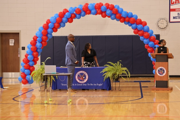 dr. Jones standing in front of a balloon arch and a table waiting to give students their awards