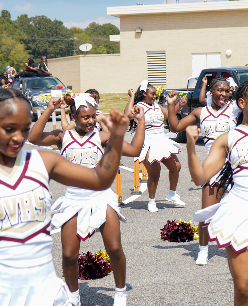 Cheerleaders perform a routine in a high school parking lot.