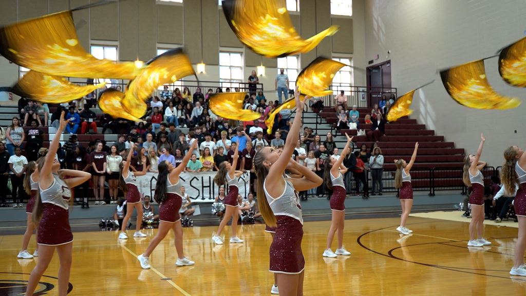 Color guard members perform at a pep rally in a school gym