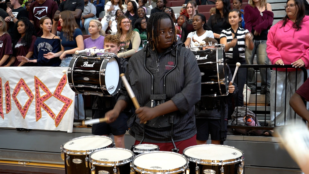 A student plays drums at a pep rally