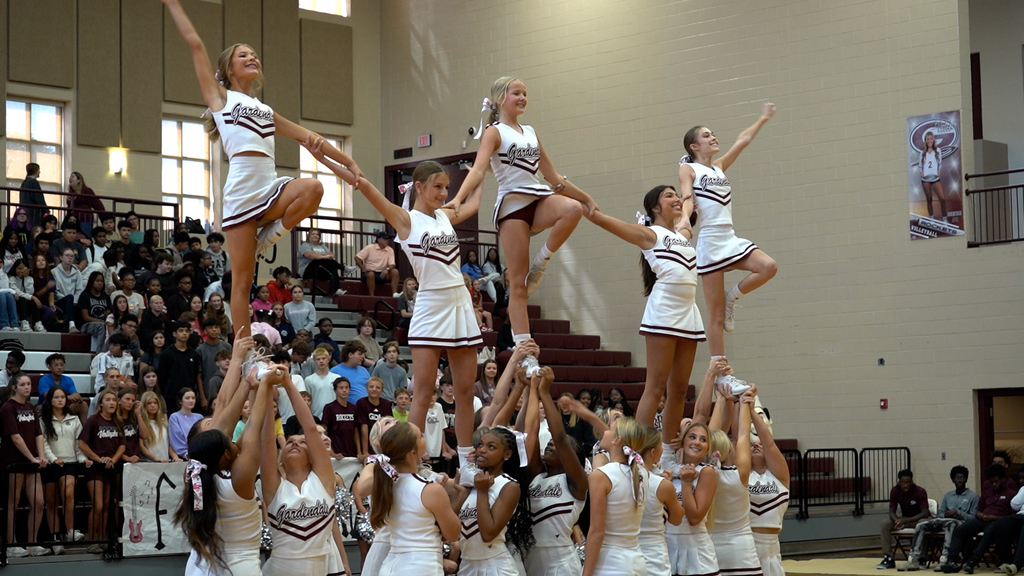Cheerleaders perform a stunt at a pep rally
