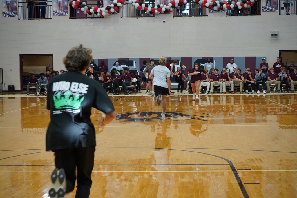 Students run across the gym floor at a pep rally