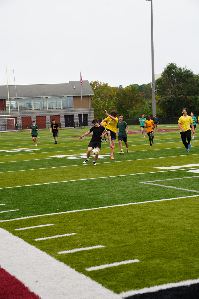 Students play soccer on a field.