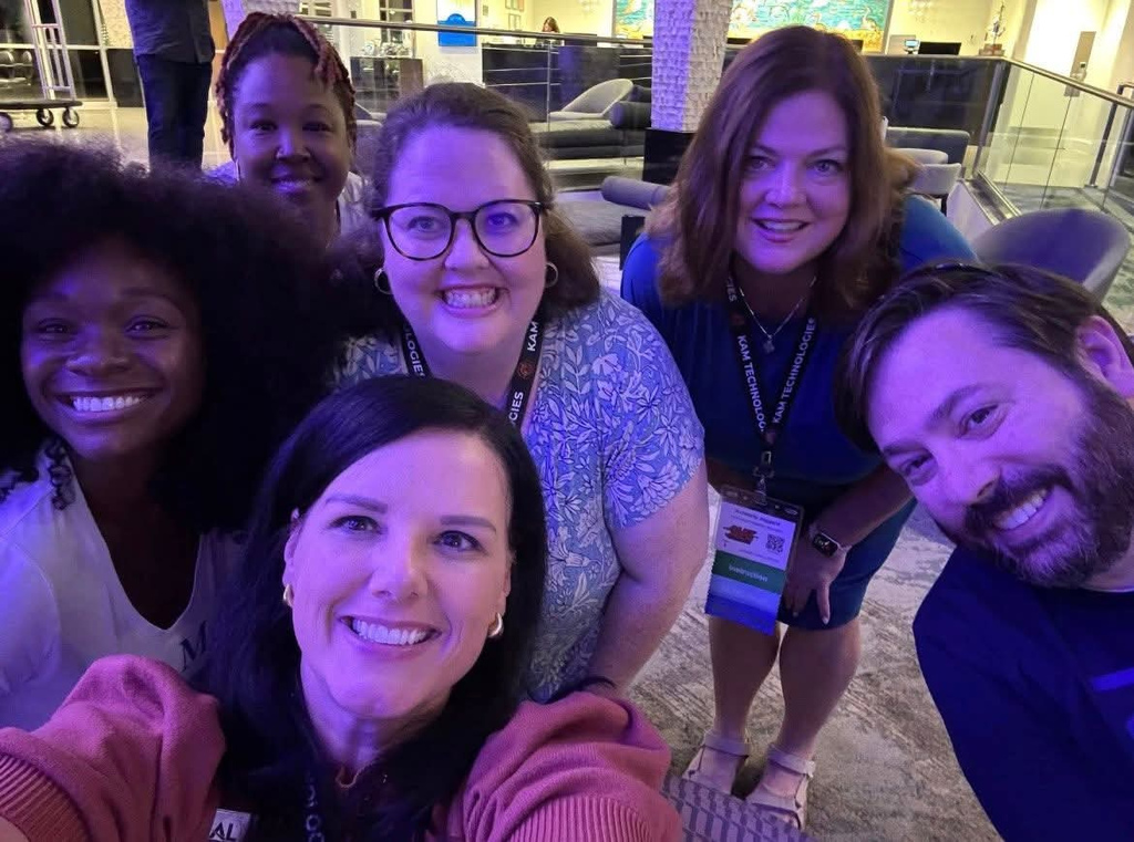 A group of people smile while taking a selfie in a hotel lobby.