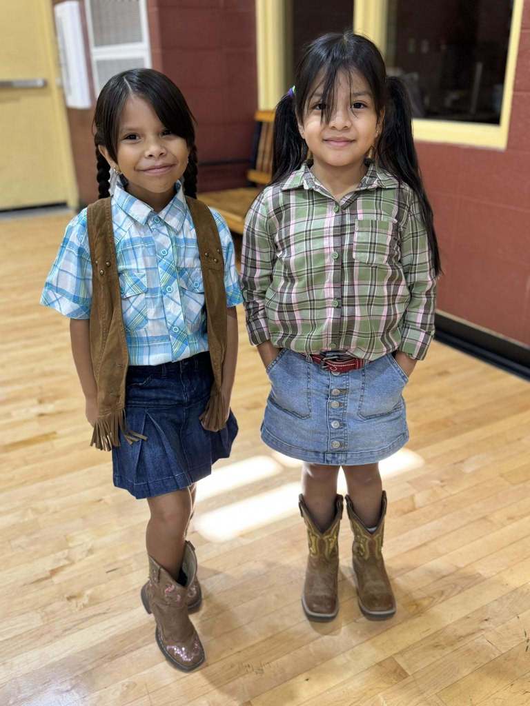 Two elementary school students smile while standing in a school gym.