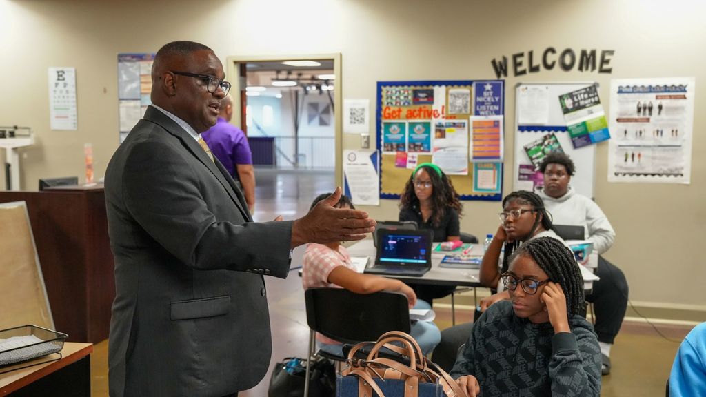 JEFCOED Superintendent Dr. Gonsoulin stands in a room and talks to students who are sitting at tables. 