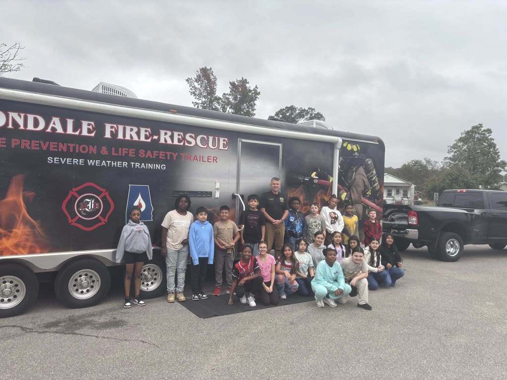 A group of students and an adult stand outside of an Irondale Fire-Rescue Fire Prevention and Life Safety Trailer.