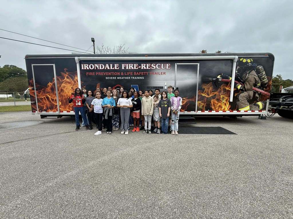 A group of students and an adult stand outside of an Irondale Fire-Rescue Fire Prevention and Life Safety Trailer.